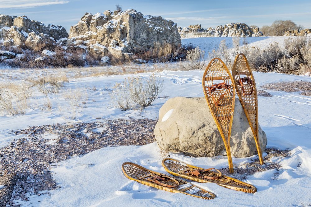 Two pairs of vintage snowshoes propped against a rock.