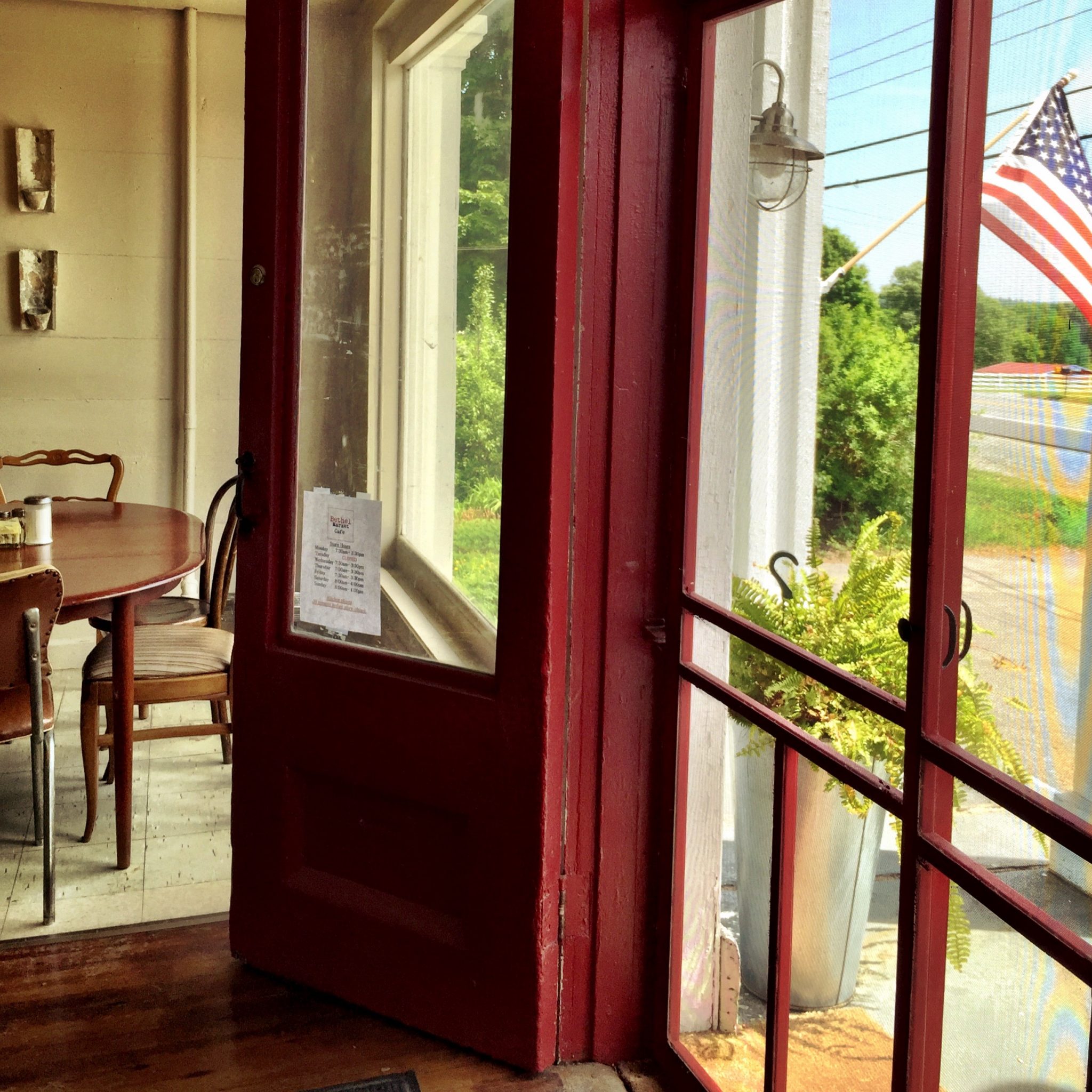 Entrance to a coffee shop with a red screen door with an American flag