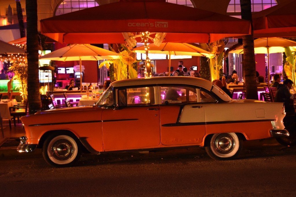 Vintage car parked in front of a neon-lit building in Miami's South Beach, a destination associated with the 1980s because of the TV show Miami Vice