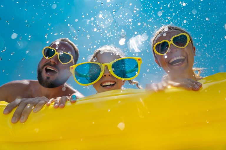 Family wearing bright sunglasses on spring break beach vacation.