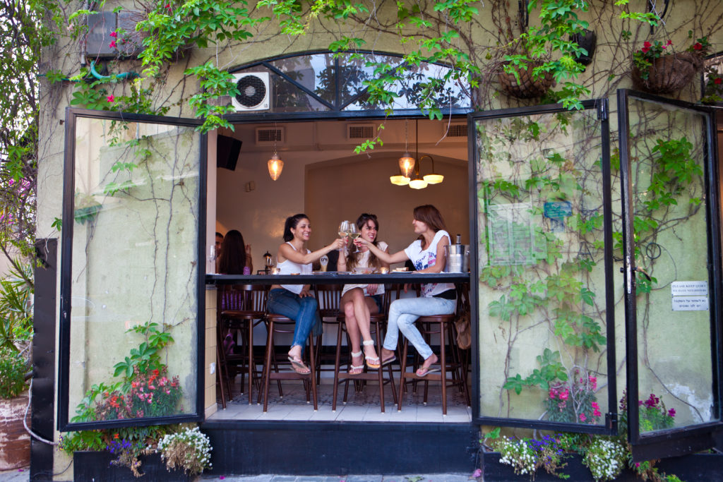 three women enjoying a drink at a cafe in Israel