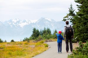 Father and son in front of mountains in Olympic National Park, one of the federal US parks that offer free admission with the Every Kid Outdoors Pass